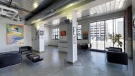 Located at 369 E Gay St in the heart of Columbus, Ohio, this single-floor commercial space offers an open, versatile layout with a distinctly industrial-modern character. Polished concrete floors extend throughout the interior, lending a sleek, clean foundation that complements the space's contemporary design. Exposed ductwork and structural ceiling elements add an authentic urban aesthetic, while structural columns punctuate the floor plan, defining areas without interrupting the overall sense of openness.

Large windows along the street-facing wall flood the interior with natural light and provide clear views of the surrounding downtown Columbus streetscape, creating a strong visual connection between the space and its urban environment. The bright white walls serve as an ideal backdrop for displaying artwork or merchandise, as evidenced by the framed pieces currently on display throughout the space.

A built-in display counter and dark-toned furniture provide functional focal points within the layout, offering areas for client engagement or product presentation. The space is well-suited for use as a gallery, creative studio, showroom, or boutique retail environment. Its prime downtown Columbus location on E Gay St places it within easy reach of the city's cultural and business districts, making it a compelling option for businesses seeking a high-visibility, design-forward presence.
