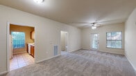 This single-floor residence offers a practical and comfortable layout across several well-defined living spaces. The spacious living room serves as the heart of the home, featuring plush wall-to-wall carpeting, neutral beige walls, and a ceiling fan with light fixture. A glass-paneled exterior door fills the room with natural light and provides outdoor access. The living area connects seamlessly to a secondary carpeted room, visible through an open doorway, offering flexible use as a dining area or additional living space.

The galley-style kitchen is efficiently designed with warm wood cabinetry lining both walls, ample counter space, white appliances including a range, refrigerator, dishwasher, and microwave, and tile flooring. A window above the counter allows natural light to brighten the workspace.

The two bedrooms are generously sized, each finished with soft carpeting, ceiling fans, and closet access. One bedroom features a window with outdoor views, enhancing the sense of openness.

The unit includes two full bathrooms. The first features a single-sink vanity with wood cabinetry, a window, and tile floors. The second bathroom offers a tub-shower combination with tiled surround, a vanity sink, and matching tile flooring. Together, the spaces present a clean, functional, and well-maintained living environment.