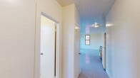 Located at 23 Bedell Street in Hempstead, NY, this one-bedroom, one-bathroom unit offers a practical and efficiently laid-out single-floor living space. The open main area combines the living and kitchen zones, finished with speckled vinyl tile flooring throughout that is easy to maintain and reflects natural light. The kitchen is equipped with warm wood cabinetry, a dark-topped sink with under-counter storage, a white refrigerator, and a freestanding gas range, providing all the essential cooking amenities in a compact footprint. Multiple double-hung windows with dark frames bring in natural light and outdoor views from multiple angles, keeping the space feeling bright and airy despite its modest size. Baseboard heating runs along the walls, ensuring consistent warmth throughout the colder months. The bedroom area features a double-door closet and additional windows overlooking the outdoors. The bathroom is finished with large-format white ceramic wall tiles surrounding a full soaking tub, complemented by a window that introduces natural light and ventilation. A wood-toned vanity with a white basin completes the bathroom. The unit's clean, neutral palette and functional layout make it a practical living space in the heart of Hempstead.
