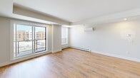 This well-appointed one-bedroom, one-bathroom unit at 8 Walker Ave in Halifax, Nova Scotia, offers a thoughtfully designed open-concept layout finished with modern, clean aesthetics throughout. Warm hardwood-style flooring flows seamlessly across the entire space, complementing the bright white walls and recessed lighting that create a fresh, contemporary feel.

The kitchen is a standout feature, showcasing a sleek peninsula with a white quartz countertop and a deep stainless steel double sink, dark navy cabinetry, light wood upper cabinets, and stainless steel appliances including a refrigerator and range. The kitchen opens directly into the spacious living area, which benefits from large windows and a sliding glass door that invite natural light and provide views of the surrounding neighbourhood. A wall-mounted mini-split unit and baseboard heaters ensure year-round comfort.

The bedroom is a comfortable and quiet retreat, with ample space and easy access to the well-designed bathroom. The bathroom features a light wood vanity with a white countertop, a large mirror, and a fully tiled glass-enclosed walk-in shower. In-unit laundry with a stacked Whirlpool washer and dryer adds everyday convenience, completing this functional and stylish Halifax residence.