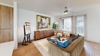 This two-story residence in Dallas, Texas offers a thoughtfully designed layout spread across two floors. The main level features an open-concept living, dining, and kitchen area bathed in natural light from large windows dressed with stylish curtains. The kitchen is outfitted with warm wood cabinetry, quartz countertops, stainless steel appliances, a center island with bar seating, and a white tile backsplash. The adjacent dining area provides a dedicated space for entertaining, accented by a gallery wall and generous natural light. The living room is bright and airy, featuring wood-style flooring, a ceiling fan, and large windows with outdoor views. Three full bathrooms serve the home, including one with a soaking tub and tile surround and another with a walk-in shower. Both bedrooms are well-proportioned and comfortable, with the primary suite featuring a walk-in closet and a ceiling fan. Additional highlights include a dedicated laundry area, ample closet storage, a hallway connecting the upper floor, and a private balcony. The two staircases provide convenient circulation between floors, and the clean, neutral palette throughout creates a cohesive and inviting atmosphere.