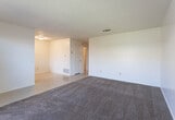 Located at 5501 48th St in Lubbock, TX, this single-story unit offers a straightforward, functional layout suited for everyday living. The open living and dining area combines tile flooring with plush carpeting, creating a natural division between spaces. A large window at the front allows natural light to fill the room, while a floor vent and ceiling-mounted HVAC register ensure climate control throughout.

The kitchen is positioned adjacent to the main living area and features dark wood cabinetry extending to the ceiling for ample storage, light-toned countertops, a built-in sink, and a black dishwasher. Tile flooring continues throughout the kitchen, complementing the cabinetry's warm tones.

The bedrooms are generously sized, each finished with wall-to-wall carpet and equipped with ceiling fans that provide both lighting and ventilation. Windows in the bedrooms allow for natural light, and one bedroom includes dual closet doors, offering practical storage solutions.

The bathroom is well-appointed with a tiled tub-shower combination, a wood-toned vanity with a wide mirror, overhead cabinet storage, and tile flooring. A textured ceiling is consistent throughout the unit, adding a classic residential character to the overall interior.