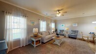 This single-floor residence offers a thoughtfully designed layout with cohesive neutral tones and consistent finishes across every room. The welcoming entryway features crown molding, wood-look flooring, and a framed accent wall, providing a smooth transition into the main living areas.

The living room is generously proportioned, with plush carpeting, crown molding, a ceiling fan, and multiple windows fitted with plantation shutters and sheer drape panels that allow ample natural light to filter through. Adjacent to the living space, a cozy dining nook features wood-look flooring and a pendant chandelier overhead, creating an intimate setting for everyday dining.

The kitchen is well-equipped, showcasing granite countertops, white shaker-style cabinetry, wood-look flooring, and stainless steel appliances including a refrigerator and microwave. A window above the sink provides natural light and an exterior view.

Both bedrooms are carpeted and feature crown molding and ceiling fans, offering comfortable, light-filled retreats. Each is served by its own full bathroom, both finished with granite-topped vanities, white cabinetry, and a tub-shower combination. One bathroom features wood-look flooring, while the other presents a clean, classic aesthetic with matching neutral tones throughout, ensuring a harmonious and functional living experience.