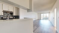 Located in the North Hollywood neighborhood of Los Angeles, this 2-bedroom, 2-bathroom residence offers a well-designed single-floor layout with modern finishes throughout. The open-concept living and kitchen area forms the heart of the home, where light gray wood-style flooring flows continuously underfoot. The kitchen features white cabinetry, a bold dark mosaic tile backsplash, stainless steel appliances including a gas range and refrigerator, and a peninsula with a white quartz countertop that doubles as a breakfast bar. A textured ceiling adds character to the space, while a sliding glass door in the living area fills the room with natural light and opens onto a private balcony with open-air views of the surrounding neighborhood and palm trees. Both bedrooms are well-proportioned, with the spacious primary bedroom offering ample room to furnish comfortably. The bedrooms feature the same wood-style flooring and are fitted with mirrored sliding closet doors that enhance the sense of light and space. The bathrooms are cleanly finished with wood-look tile flooring, white vanities, and tiled tub-shower combinations with linear stone-look tile surrounds. The overall ambiance of the residence is bright, clean, and contemporary, making it a practical and comfortable home in a central Los Angeles location.