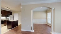Located at Towne Lake Heights in Woodstock, GA, this one-bedroom, one-bathroom unit offers a thoughtfully designed single-floor layout with refined architectural details throughout. Rich hardwood-style flooring flows through the living areas and bedroom, complemented by warm neutral wall tones and crisp white trim.

The living area is a standout, featuring a tray ceiling with a ceiling fan, crown molding, and a large window that fills the room with natural light and views of surrounding greenery. An elegant arched entryway supported by a decorative column connects to a second living area, which is adorned with wainscoting panels that add a classic, polished character.

The kitchen is well-equipped with dark espresso cabinetry, granite countertops, a center island, tile flooring, stainless steel appliances, and recessed lighting — offering both style and functionality. A set of double doors off the kitchen provides additional storage.

The bedroom features a tray ceiling with a ceiling fan and direct access to a spacious walk-in closet outfitted with wire shelving on multiple walls for generous storage. The bathroom includes a tiled tub-surround with a decorative diamond-pattern accent border, a granite-topped vanity, and hardwood-style flooring, completing this well-appointed home.