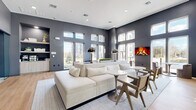 Located at 72 Eagle Rock Ave in East Hanover, NJ, this single-floor lounge space offers a sophisticated and contemporary design that makes a strong architectural statement. The living area is anchored by soaring ceilings and floor-to-ceiling windows that flood the interior with natural light, offering views of the surrounding community. Deep charcoal-gray walls create a bold contrast against the light-toned hardwood flooring, lending the space a refined, modern aesthetic throughout.

The main living area is thoughtfully arranged with a generous sectional sofa, sleek pedestal side tables, and contemporary accent chairs positioned around a centrally placed area rug. A wall-mounted electric fireplace adds warmth and visual interest to one end of the room, while stylish dome pendant lamps and wall sconces provide layered lighting.

A built-in nook along one wall houses a coffee station with cabinetry and open display shelving above, adding both functionality and decorative appeal. Glass-paneled partition walls and dark-framed sliding doors separate an adjacent workspace or conference area, maintaining visual connectivity while defining distinct zones within the open floor plan.

The overall ambiance is clean, airy, and upscale, blending comfort with professional-grade design — making this a highly versatile and welcoming communal environment.
