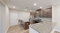 Located at 515 Stallion Cir W in Toms River, New Jersey, this single-floor residence offers a cohesive and modern interior design with high-quality finishes throughout. The open-concept kitchen is a standout feature, showcasing rich dark-brown shaker-style cabinetry, granite countertops, a tiled backsplash, and a full suite of stainless steel appliances including a gas range, built-in microwave, French door refrigerator with ice and water dispenser, and dishwasher. A central island with matching granite provides additional prep space and casual seating, while a peninsula with an undermount sink adds further functionality. Light wood-style flooring runs through the main living areas, contributing to a clean, contemporary aesthetic. The living area is bright and open, with recessed lighting and sliding door access to the exterior. Bedrooms are finished with plush carpeting and feature vertical blinds on sliding doors that invite natural light. The primary bathroom is well-appointed with a double-sink vanity, granite countertops, dark wood cabinetry, large-format tile flooring, and a glass-enclosed walk-in shower. A secondary bathroom mirrors the same refined design with a single vanity and granite countertop. The space presents a polished, move-in-ready environment with consistent, upscale finishes from room to room.