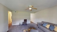 Located at 1834 Wilmington Hwy in Jacksonville, NC, this single-story home offers a practical and comfortable layout designed for everyday living. The living room serves as the heart of the home, featuring soft carpeted flooring, a ceiling fan with light fixture, and windows dressed with light curtains that allow natural light to fill the space. The room provides ample space for relaxed seating arrangements and opens naturally into the rest of the home.

The kitchen is outfitted with white cabinetry, light countertops, and hardwood-style flooring. It includes an electric range, a double-basin sink, and generous cabinet storage, making it a fully functional cooking space.

The bedrooms are carpeted and finished with vertical panel walls, offering a cozy atmosphere. Each room features windows with decorative curtain treatments that bring in natural light. One of the flexible rooms is well-suited for use as a home office or sitting area, complete with window views and built-in shelving.

The bathroom features a tiled tub-and-shower combination with classic subway-style wall tiles and chrome fixtures. Throughout the home, textured ceilings, consistent neutral tones, and carpet flooring contribute to a cohesive and livable interior aesthetic.
