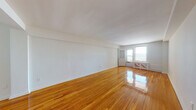Located at 210 Shore Road in Long Beach, NY, this single-floor apartment at Boardwalk Apartments offers a thoughtfully designed layout with consistent hardwood flooring throughout. A straight entry hallway, illuminated by a ceiling-mounted light fixture, leads into the main living areas and establishes a clean, organized flow through the unit.

The spacious living room is a standout feature, characterized by gleaming hardwood floors, bright white walls, and large windows that frame direct ocean views. Natural light fills the room, and a glass door provides access to what appears to be an outdoor area, further enhancing the coastal ambiance.

The kitchen is fitted with white cabinetry, dark countertops, a subway tile backsplash, and full-size appliances including a gas range and refrigerator. A window above the sink allows natural light in and provides street-facing views. The flooring transitions to a light wood-toned vinyl, complementing the clean, functional design.

The bedrooms feature warm hardwood floors, large windows, and multiple closets, including sliding-door and hinged configurations, providing generous storage. Additional rooms offer city-facing views.

Two bathrooms serve the unit: one with white subway tile walls, a vanity with medicine cabinet, and another with a granite-topped vanity and a glass-enclosed shower, both finished in a clean, classic style.