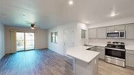 This well-appointed 2-bedroom, 1-bathroom residence at 5555 N Dante Ave in Fresno, California offers a thoughtfully designed single-floor layout. The open-concept living area seamlessly connects the kitchen, dining, and living spaces, all finished with durable wood-style flooring that runs throughout. The kitchen is a standout feature, equipped with stainless steel appliances including a range, microwave, and refrigerator, complemented by gray shaker-style cabinetry, white quartz countertops, and a peninsula with seating — ideal for casual dining or meal prep. Recessed lighting illuminates the space effectively. The living area is bright and airy, with a ceiling fan and sliding glass doors opening onto a private balcony with outdoor views. Both bedrooms are comfortable and well-lit; the primary bedroom features a ceiling fan and balcony access, while the second bedroom includes plush carpeting, a ceiling fan, and a large window with blinds. Each bedroom benefits from dedicated closet space with sliding panel doors. The full bathroom includes a tub/shower combo with glass sliding doors. A dedicated laundry area and hallway complete the functional layout, making this a practical and attractive home.