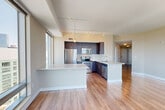 Located in Boston's Back Bay neighborhood, this 2-bedroom, 2-bathroom residence offers a well-designed single-floor layout with modern finishes throughout. Hardwood flooring extends across the entire space, complementing the clean, neutral color palette of warm beige and white tones.

The open-concept living, dining, and kitchen area forms the heart of the home. The kitchen is outfitted with dark espresso cabinetry, stainless steel appliances including a refrigerator, range, microwave, and dishwasher, a light-colored countertop island, and track lighting overhead. A large picture window in the kitchen frames a striking panoramic view of the Boston skyline and greenery below, filling the space with natural light.

The generously sized primary bedroom features floor-to-ceiling windows showcasing expansive city views, along with a dedicated walk-in closet equipped with wire shelving and hanging rods. The second bedroom also benefits from large windows with open city views. Three closets in total provide ample storage throughout the residence.

Both bathrooms are finished with dark vanity cabinetry, white countertops, and hardwood flooring. The primary bathroom includes a glass-enclosed walk-in shower with city views. A dedicated laundry area and a welcoming hallway complete the layout, making this a highly functional and light-filled urban residence.