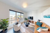 Located at 13166 NE 15th St in Bellevue, WA, this thoughtfully designed one-bedroom, one-bathroom unit maximizes every inch of its compact footprint. Light wood-tone flooring runs throughout, complemented by crisp white walls and recessed lighting that create a bright, cohesive aesthetic.

The entrance hallway sets a modern tone with floor-to-ceiling wood-paneled cabinetry providing ample storage, alongside a stainless steel refrigerator integrated into the kitchen cabinetry wall. The kitchen is equipped with stainless steel appliances, including a gas range and over-the-range microwave, with a clean tile backsplash tying the space together.

The living room is a highlight of the unit, featuring large windows that invite abundant natural light and offer open views of the surrounding Bellevue neighborhood. A sliding barn door connects the living area to the bedroom, adding a stylish, space-conscious touch. The bedroom includes a distinctive accent ceiling detail and direct visual access to the kitchen.

The bathroom is well-appointed with a dark wood-grain vanity, a backlit mirror, a tall storage tower, and an in-unit stacked washer and dryer conveniently tucked behind the vanity. Two closets provide additional storage throughout the unit. Clean lines and contemporary finishes define every room in this efficiently planned Bellevue residence.