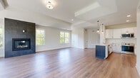 Located at 300 Dunnwood Green in Pittsford, NY, this thoughtfully designed single-floor residence offers 2 bedrooms and 2 bathrooms across a generous, open layout. The combined kitchen and living area serves as the heart of the home, highlighted by a striking tile-surround fireplace flanked by a bank of windows that fill the space with natural light and views of lush greenery. Tray ceilings add architectural depth to the living area, while durable hardwood-style flooring flows consistently throughout. The kitchen features white shaker cabinetry, subway tile backsplash, quartz countertops, stainless steel appliances, a navy blue island with pendant lighting, and ample counter space. The spacious primary bedroom includes vaulted ceilings, a ceiling fan, large windows with outdoor views, and access to a walk-in closet outfitted with wire shelving systems. Both bathrooms are clean and functional, with one featuring a full soaking tub with white tile surround. A dedicated laundry room with a window, washer and dryer, and overhead shelving adds everyday convenience. Multiple hallways connect the well-organized floor plan, and an exterior door provides direct outdoor access from the living area.