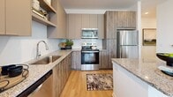 Located at 2307 Ridgemont Ave in Charlotte, NC, this 2-bedroom, 2-bathroom residence offers a clean, modern aesthetic throughout its single-floor layout. Light hardwood flooring flows seamlessly across the main living areas, complementing the bright, white walls and abundant natural light admitted through large windows fitted with blinds and sheer curtains.

The living room is a welcoming, open space anchored by a ceiling fan and French doors that invite outdoor views and additional light. The kitchen is well-equipped with stainless steel appliances, granite countertops, a subway tile backsplash, and contemporary two-tone cabinetry — combining style with functionality. An adjacent dining area completes the open-concept entertaining space.

The primary bedroom is a comfortable retreat featuring a ceiling fan and large windows with outdoor views. Both bedrooms offer walk-in closets with wire shelving systems, providing generous storage. A second bedroom serves well as a flexible guest room or home office, as seen with a dedicated workspace bathed in natural light.

Each bathroom is finished with granite-topped wood vanities and tiled tub-shower combinations. The overall ambiance of the home is calm and contemporary, with clean lines, neutral tones, and an abundance of natural light creating a welcoming, livable environment throughout.