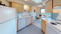 Located at 10620 West 12th Avenue in Spokane, WA, this single-floor unit offers a well-organized and comfortable living environment. The living room is generously proportioned, featuring light-toned carpet, soft yellow walls, and an open layout that connects seamlessly to the rest of the unit. A large mirror accent wall enhances the sense of depth, while natural light filters in through windows that overlook greenery outside.

The kitchen is thoughtfully designed with light wood cabinetry, white countertops, and a full suite of appliances including a refrigerator and dishwasher. A skylight and track lighting brighten the workspace, and a dedicated dining area adjacent to the kitchen provides access to a private balcony, adding an outdoor extension to the living space.

The bedroom is a calm and carpeted retreat, featuring a sliding-door closet with ample storage, a window that brings in natural light, and a wall-mounted air conditioning unit for year-round comfort. The full bathroom is clean and functional, appointed with white tile flooring, a single-sink vanity with light wood cabinetry, and a tub-shower combination. A hallway connects all rooms efficiently, completing this well-laid-out and inviting unit.