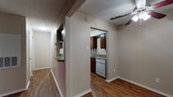 This single-floor residential unit offers a practical and cohesive layout connected by rich, wood-style laminate flooring that extends throughout every room. The living area is generously sized and features a ceiling fan with integrated lighting, neutral beige walls, and a large sliding glass door fitted with vertical blinds that allow for natural light. An adjacent dining area, also equipped with a ceiling fan, opens directly to the kitchen through an arched passageway, creating a connected and efficient flow between spaces.

The galley-style kitchen is well-appointed with rich dark-wood cabinetry lining both sides, granite-look countertops, a stainless steel sink, and white appliances including a coil-top range, refrigerator, and dishwasher. A range hood is mounted above the stove, and ample upper and lower cabinet storage maximizes functionality.

The bedrooms are comfortably sized, each with neutral walls, wood-style flooring, and either a ceiling fan or a window with blinds for natural light. The bathroom includes a single-sink vanity with a stone-look countertop, a mirrored medicine cabinet, and a full tub-shower combination. Textured ceilings and clean white baseboards are consistent design elements found throughout the unit, contributing to a uniform and tidy overall aesthetic.