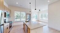 Located at 2220 Berryhill Road in Charlotte, NC, this well-appointed 2-bedroom, 2-bathroom residence offers a thoughtfully designed single-floor layout with modern finishes throughout. The open-concept kitchen serves as the heart of the home, showcasing a large center island with a light quartz countertop, a matte black faucet, and an undermount sink. Warm-toned cabinetry extends to the ceiling, complemented by stainless steel appliances and sleek pendant lighting. Light wood-look flooring flows through the main living areas, creating a bright, cohesive aesthetic. Abundant windows invite natural light throughout, and a ceiling fan anchors the spacious living area, which opens to a private balcony with peaceful views of mature trees and the surrounding neighborhood. The primary bedroom features plush carpet, elevated ceilings, and direct access to a well-organized walk-in closet with built-in shelving, as well as a private en-suite bathroom with a wood-toned vanity and matte black hardware. The second bedroom is equally bright, with a ceiling fan and a large window framing a lush outdoor view. A second full bathroom offers a tiled tub-shower combination. Additional conveniences include dedicated laundry, a utility room, and ample closet storage throughout.