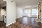 Located at 632 23rd St E in Tuscaloosa, Alabama, this single-story home offers a well-organized layout with consistent finishes throughout. Dark hardwood-style flooring runs through the living areas, bedrooms, and hallways, providing a cohesive look across the entire space. A long, well-lit hallway connects the main living areas to the bedrooms, lined with neutral gray walls and clean white baseboards. The living room is generously sized, featuring large windows and a glass-paneled door that allows natural light to fill the space. The galley-style kitchen is equipped with warm wood cabinetry, light countertops, a double sink, and a white electric range, with an adjacent windowed area that enhances the feel of the space. The bedrooms are well-proportioned, each featuring windows with blinds that bring in natural light, textured ceilings, and the same dark flooring found throughout the home. Two bathrooms serve the residence — one features a white vanity with a framed mirror and separate water closet, while the other includes a full bathtub and shower combination with rich, earth-toned stone-look wall surrounds, a white vanity, and wood-style flooring. Textured ceilings are present in most rooms, and the neutral color palette throughout creates a clean, move-in-ready atmosphere.