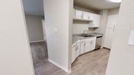 Located at 611 Lead Ave SW in Albuquerque, New Mexico, this single-floor, 2-bedroom, 2-bathroom residence offers a comfortable and functional layout. The kitchen is a standout feature, equipped with crisp white shaker-style cabinetry, granite-look countertops, stainless steel appliances including a dishwasher, a black electric range, and light wood-look luxury vinyl plank flooring that extends throughout the main living areas. A central dividing wall separates the kitchen from the adjacent living space, which transitions seamlessly into carpeted areas for added warmth and comfort. Both bedrooms are carpeted and feature ceiling fans with integrated lighting. The primary bedroom is generously sized and includes a walk-in closet outfitted with dual hanging rods and upper shelving, providing ample storage. One bedroom benefits from a large window with blinds, allowing natural light and views of surrounding greenery. Each bathroom is finished with a tub-shower combination, white tile surround, granite-look vanity countertops, white cabinetry, and wood-look flooring. The neutral color palette and clean finishes throughout create a cohesive, move-in-ready environment well suited for comfortable everyday living.