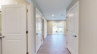 This single-floor residence offers a clean, contemporary design highlighted by light wood-style flooring that flows consistently throughout the space. The open layout connects key living areas seamlessly, beginning with a central hallway lined with panel-style white doors and recessed lighting that guides residents toward the main living area.

The living room is a spacious, light-filled area anchored by sliding glass doors dressed with vertical blinds, framing views of a green outdoor setting. Recessed ceiling lights complement the natural light, creating a bright and welcoming atmosphere.

The kitchen is well-equipped with rich, dark wood cabinetry extending to the ceiling for generous storage, granite-speckled countertops, and a full suite of stainless steel appliances including a side-by-side refrigerator, electric range, built-in microwave, and dishwasher. An adjacent peninsula adds additional counter space.

The bedrooms are comfortably sized, each featuring wood-style flooring, neutral-toned walls, and windows fitted with blinds. The bathroom includes a double-sink vanity topped with granite, a tub and shower combination with marble-style tile surround, and accessibility grab bars, all finished with warm, neutral tones throughout.