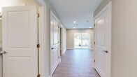 This single-floor residence offers a clean, contemporary design highlighted by light wood-style flooring that flows consistently throughout the space. The open layout connects key living areas seamlessly, beginning with a central hallway lined with panel-style white doors and recessed lighting that guides residents toward the main living area.

The living room is a spacious, light-filled area anchored by sliding glass doors dressed with vertical blinds, framing views of a green outdoor setting. Recessed ceiling lights complement the natural light, creating a bright and welcoming atmosphere.

The kitchen is well-equipped with rich, dark wood cabinetry extending to the ceiling for generous storage, granite-speckled countertops, and a full suite of stainless steel appliances including a side-by-side refrigerator, electric range, built-in microwave, and dishwasher. An adjacent peninsula adds additional counter space.

The bedrooms are comfortably sized, each featuring wood-style flooring, neutral-toned walls, and windows fitted with blinds. The bathroom includes a double-sink vanity topped with granite, a tub and shower combination with marble-style tile surround, and accessibility grab bars, all finished with warm, neutral tones throughout.