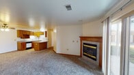 This well-organized single-floor residence offers a practical and comfortable layout designed for everyday living. The open living area serves as the heart of the home, anchored by a tile-surround fireplace with a warm wood mantel, adding a classic focal point to the carpeted space. A sliding glass door floods the living area with natural light and provides direct access to the outdoors. The kitchen is efficiently designed in a galley style, featuring ample oak cabinetry both above and below the counter, light-colored countertops, a double-basin sink, and white appliances including a range and refrigerator, with tile flooring throughout. A peninsula with additional storage extends the kitchen's functionality toward the living area. The primary bedroom is generously sized, with two windows that invite natural light, a ceiling fan, and a sliding closet. A second bedroom also features carpeted flooring, a window with blinds, and a sliding closet, with convenient access to a full bathroom. The full bathroom is clean and functional, featuring a vanity with oak cabinetry, a large mirror, a soaking tub, and light tile flooring. Throughout the home, warm wood trim and neutral tones create a cohesive and inviting atmosphere.