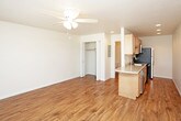 This single-floor unit offers a functional and comfortable layout designed for everyday living. The open living area is highlighted by warm hardwood-style flooring that extends throughout the space, a textured ceiling, and a ceiling fan with integrated lighting that provides both comfort and illumination. A large window near the entry door allows natural light to fill the room, creating a bright and welcoming atmosphere, while a wall-mounted HVAC unit ensures year-round climate control. A closet with bi-fold doors offers convenient storage directly off the living area. The kitchen flows seamlessly from the main living space and features light wood cabinetry, granite-look countertops, and stainless steel appliances including an electric range, over-the-range microwave, and refrigerator. A breakfast bar provides a casual dining option and helps define the transition between the kitchen and living area. The bathroom is clean and straightforward, offering a single-sink vanity with light wood cabinetry, a large mirror with overhead lighting, and a full tub-shower combination. Throughout the unit, neutral tones and consistent flooring create a cohesive and move-in-ready environment.