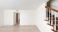 Located at 2030 W Broad Ave in Albany, Georgia, this two-story home offers a practical and well-organized layout spread across two floors. The main level features a bright, open living room with light wood-look flooring, a ceiling fan, and a large wall mirror that enhances the sense of space. The adjoining dining area connects seamlessly to the galley-style kitchen, which is equipped with gray cabinetry, white countertops, a dishwasher, range, and refrigerator, all accented by wood-look tile flooring and crown molding. A convenient half bathroom is also found on the main floor. A staircase with a wood railing leads to the upper level, where two carpeted bedrooms and two full bathrooms are located. The generously sized primary bedroom features two double bi-fold closets for ample storage. A dedicated walk-in closet with built-in shelving and a hanging rod provides additional organization. The primary bathroom includes a wide vanity with a white countertop, a large mirror, and a separate tiled shower and tub area. A hallway closet rounds out the upper floor. Throughout the home, warm-toned wood doors add a classic contrast to the crisp white walls and neutral finishes, creating a clean and functional living environment.