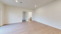 This single-story, one-bedroom, one-bathroom residence offers a thoughtfully designed open floor plan that maximizes its comfortable footprint. The interior is finished with light wood-style luxury vinyl plank flooring in the main living areas, contributing to a bright, clean aesthetic throughout.

The combined kitchen and living room serves as the heart of the home. The kitchen is outfitted with stainless steel appliances, including a refrigerator, electric range, and over-the-range microwave, complemented by gray shaker-style cabinetry and white quartz countertops. A central island with a built-in sink and pendant lighting overhead provides both additional workspace and a casual dining option, while a sliding glass door in the living area invites natural light and provides outdoor access.

The bedroom features neutral carpet flooring and includes a double-door closet for storage. Recessed lighting and a connected full bathroom with additional closet access enhance the room's functionality.

The bathroom is finished with light wood-style flooring, a gray vanity with white countertop, and a full shower-tub combination. A dedicated laundry room houses a full-size washer and dryer with overhead wire shelving, adding significant everyday convenience to the unit.