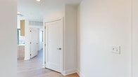 Located on Hillsboro Pike in Nashville's 37215 corridor, this modern two-bedroom, one-bathroom residence delivers a refined urban living experience with contemporary design and sweeping panoramic views of the Nashville skyline and surrounding neighborhoods. Light hardwood flooring flows throughout the single-level layout, tying together each thoughtfully designed space.

The open-concept kitchen is a standout feature, outfitted with warm wood cabinetry that extends floor to ceiling, a marble-look tile backsplash, quartz countertops, stainless steel appliances including a gas range and full-size refrigerator, and a central island with an undermount sink — ideal for both cooking and entertaining.

The living area and bedrooms are bathed in abundant natural light, courtesy of dramatic floor-to-ceiling windows with dark metal frames that frame spectacular elevated views of the Nashville cityscape and rolling horizon. The primary bedroom offers a generous footprint, while the second bedroom also benefits from large windows and bright, airy exposure.

The bathroom features a sleek, elongated vanity with wood cabinetry, a quartz countertop, and large-format tile flooring. A dedicated laundry room with a full-size washer and dryer adds everyday convenience. Clean white walls, crisp millwork, and modern hardware complete the polished, contemporary aesthetic throughout.