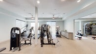 Located at 1619 N Frazier Street in Conroe, Texas, this fitness center offers a thoughtfully designed, single-floor workout facility with generous square footage to accommodate a wide variety of exercise equipment and training zones. The interior features a clean, modern aesthetic with soft gray walls, light carpet flooring, and tray ceilings outfitted with recessed lighting and ceiling fans that maintain a comfortable, well-ventilated environment throughout.

The main workout area is anchored by a comprehensive selection of cardio equipment, including treadmills, stair climbers, and elliptical machines, alongside multi-station cable and weight machines for strength training. A dedicated free weights section features a full dumbbell rack and floor mats, complemented by wall-length mirrors that enhance the sense of space and support proper form. A separate rowing alcove provides a focused space for low-impact, full-body training, benefiting from a large window that invites natural light. An additional area is outfitted with spin bikes and a rack of stability balls and medicine balls, ideal for group-style or functional fitness workouts. Built-in cabinetry along one wall provides convenient storage. The facility also includes a private restroom and direct access to adjacent amenity spaces, making it a fully self-contained and functional fitness destination.