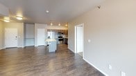 This single-floor residence offers a functional and cohesive layout with a neutral color palette of warm beige and taupe tones throughout. The kitchen serves as a practical centerpiece, equipped with a full suite of stainless steel appliances including a French door refrigerator, electric range, built-in microwave, and dishwasher. Dark espresso-toned cabinetry pairs with light countertops to create a clean, contemporary aesthetic, complemented by durable wood-look flooring that extends through the main living areas.

The living spaces include a carpeted main room and additional flexible areas with wood-look flooring, offering versatility for various furniture arrangements. Bedrooms feature plush carpeting, natural light from windows with blinds, and closets with built-in shelving for organized storage.

The bathrooms are finished with dark wood vanities topped with stone-patterned countertops. One bathroom includes a tub/shower combination with a single-sink vanity, while another features a separate toilet area. A dedicated in-unit laundry space accommodates a full-size top-loading washer and dryer set beneath wire shelving. Throughout the unit, consistent trim work, flush-mount lighting, and smoke detectors contribute to a tidy, move-in-ready environment.
