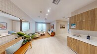 Located at 5475 N University Drive in Lauderhill, Florida, this single-floor wellness suite offers a complete and cohesive layout designed for professional comfort and client experience. The reception and living area serves as the welcoming heart of the space, featuring light-toned large-format tile flooring, recessed lighting, and soft neutral walls accented with subtle textured wallpaper. A comfortable seating arrangement centered on a woven area rug, flanked by lush indoor plants and decorative artwork, creates a calming, spa-like ambiance. Sheer floor-to-ceiling curtains frame the windows, diffusing natural light throughout the room. Adjacent to the reception area is a built-in wood-finish cabinetry station with a clean white countertop, providing functional workspace and storage. The treatment room is a serene, private space with light hardwood flooring, soft wall paneling, and sheer curtain-draped windows that invite gentle natural light — ideal for massage or therapeutic services. The bathroom is a standout feature, boasting floor-to-ceiling warm wood-toned tile, a spacious glass-enclosed walk-in shower with a rainfall showerhead, and polished stone flooring. A connecting hallway with textured wall finishes and solid doors ensures privacy between rooms. The office provides a dedicated administrative area, completing this well-appointed professional wellness environment.