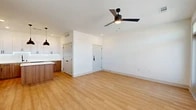 Located at 5300 Las Soleras Dr in Santa Fe, New Mexico, this thoughtfully designed one-bedroom, one-bathroom residence offers a clean, modern aesthetic with quality finishes throughout. The open-concept kitchen and living area serves as the heart of the home, featuring a striking two-tone kitchen with white upper cabinetry, warm wood-toned lower cabinets, a white quartz-topped center island, tile backsplash, stainless steel appliances, and bold black pendant lighting. Light-toned hardwood-style flooring flows throughout the main living spaces, complementing the bright white walls and recessed lighting. The spacious living area is bathed in natural light from multiple windows and a glass patio door, and is equipped with a ceiling fan. The door opens to a private patio with outdoor views. The carpeted bedroom is a generous size, featuring its own ceiling fan, multiple windows, and a panel-style door. The bathroom is elegantly appointed with a warm wood vanity, white countertop, black fixtures, and a backlit LED mirror. A walk-in closet with wire shelving provides ample storage. This well-appointed residence combines contemporary design with functional living in the heart of Santa Fe.