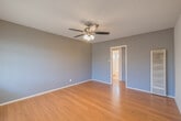 Located at 6100 West Blvd in the Hyde Park neighborhood of Los Angeles, CA, this single-floor unit offers a practical and comfortable layout across several well-defined living spaces. The living area greets you at the entry, featuring warm hardwood-style flooring that extends throughout the main rooms, a ceiling fan with integrated lighting, and large windows dressed with horizontal blinds that allow ample natural light to fill the space. The open flow connects seamlessly to adjacent rooms, making the layout feel connected and easy to navigate. The bedrooms continue the warm flooring aesthetic, each equipped with ceiling fans and windows that bring in natural light. The blue-gray accent walls provide a calm, neutral palette throughout. The kitchen is outfitted with tile flooring, gray cabinetry, a gas range, a full-size refrigerator, and granite-style countertops — providing all the essentials for everyday cooking. The bathroom features a clean, all-white tub and shower combination with a window above for ventilation and light. Textured ceilings are present throughout the unit, adding a classic character to the interior. Overall, the unit presents a straightforward, functional living environment in a well-established Los Angeles neighborhood.