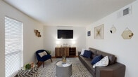 This two-floor residence offers a thoughtfully laid-out living environment with a variety of comfortable spaces across both levels. The living room serves as the heart of the home, featuring warm hardwood-style flooring, a textured ceiling, and large windows that allow natural light to fill the room. A gray leather sofa, patterned area rug, and a wall-mounted flat-screen television above a wooden media console create an inviting and functional gathering space.

The kitchen is equipped with ample white cabinetry extending to the ceiling, a double-basin sink, and a white electric range, all set on a warm hardwood floor. The clean, bright design makes the kitchen a practical and efficient space.

The bedrooms are spread across the two floors, each carpeted for comfort and fitted with ceiling fans for climate control. Natural light enters through slatted blinds on multiple windows. Each bedroom includes a built-in closet with bifold doors, offering generous storage. The primary bedroom stands out with dual windows and additional seating space, while the secondary bedrooms offer cozy, well-defined areas suitable for rest or study.

Throughout the home, the neutral white walls and consistent design choices create a cohesive and clean aesthetic, making the space feel open, bright, and move-in ready.