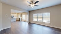 Located at 2311 Spring Rush Dr in Buford, GA, this generously sized two-story home offers eight bedrooms and three bathrooms across two well-proportioned floors. The main floor provides an expansive layout, housing the primary living spaces, while the upper floor offers additional bedrooms and flexible room configurations.

The entrance welcomes visitors with a wide hallway featuring dark hardwood-style flooring, crisp white crown molding, and an elegant staircase with wood treads and ornate wrought-iron balusters. The open-concept kitchen and living room form the heart of the home, bathed in natural light from large windows. The kitchen is outfitted with gray cabinetry, granite countertops, stainless steel appliances including a French-door refrigerator, and a tile backsplash. A ceiling fan anchors the living area, which flows seamlessly into the space.

The formal dining room features rich hardwood-style flooring and a classic chandelier. The generously sized primary bedroom stands out with plush carpeting, a tray ceiling with crown molding, a ceiling fan, and a private en-suite bathroom. Bathrooms are finished with granite vanity tops and include tub/shower combinations.

The attached garage accommodates vehicles alongside utility infrastructure. Outside, a fenced backyard with a concrete patio provides a private outdoor retreat backed by a natural tree line.