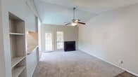This single-floor unit offers a well-organized layout designed for comfortable everyday living. The living room serves as the centerpiece of the space, boasting vaulted ceilings with a textured finish that amplify the sense of openness. A ceiling fan with a built-in light fixture is centrally mounted, providing both airflow and illumination. A black-tiled wood-burning fireplace anchors one wall, flanked by a glass-paned exterior door and a window that invites natural light and outdoor views. Plush wall-to-wall carpet extends throughout the living and bedroom areas, adding warmth underfoot.

The galley-style kitchen is efficiently arranged with warm wood cabinetry, speckled laminate countertops, a stainless steel sink, and black appliances including a range and refrigerator. Durable hardwood-style flooring runs the length of the kitchen, providing a clean contrast to the carpeted areas.

The bedroom is a spacious, quiet retreat with vaulted ceilings, a ceiling fan, and a large window fitted with vertical blinds that control natural light. The bathroom is neatly appointed with white tile surrounding a full bathtub and shower, a wood-vanity with a speckled countertop, a single basin sink, and hardwood-style flooring that ties the wet areas together cohesively.