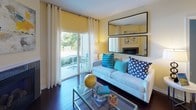 This single-floor residence is designed with a cohesive, contemporary aesthetic that balances comfort and functionality throughout its thoughtfully arranged spaces. The living area serves as a welcoming focal point, featuring rich dark hardwood floors, a corner fireplace, and a wall-mounted flat-screen television above a low-profile wooden shelving unit. A sliding glass door floods the room with natural light and provides direct access to an outdoor patio with garden views, while sheer white curtains and a yellow roller shade offer privacy when desired.

The open-concept kitchen is well-equipped with rich dark wood cabinetry extending to the ceiling, stainless steel appliances, and granite countertops. A kitchen island with a double undermount sink adds workspace and a natural gathering point. A dedicated built-in desk nook with matching cabinetry and granite surfaces offers a convenient workspace area tucked within the kitchen zone.

The bedroom is a calm, restful space with soft blue walls, plush carpet, and ample natural light from dual windows dressed with sheer drapes and blinds. The full bathroom features bold cobalt blue accent walls, wood-look tile flooring, a granite-topped double vanity with dark wood cabinetry, and a full soaking tub. A doorway within the bathroom leads directly into a spacious walk-in closet with built-in shelving, completing the suite.
