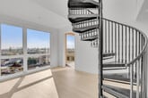 Located at 5570 Rosemead Blvd in Temple City, CA, this modern 2-bedroom, 1-bathroom unit offers a thoughtfully designed open floor plan with clean lines and a bright, contemporary aesthetic throughout. The kitchen serves as the heart of the home, featuring a large white quartz island with an undermount sink, stainless steel appliances including a gas range, built-in microwave, and side-by-side refrigerator, complemented by flat-front white cabinetry and pendant lighting. A stacked in-unit washer and dryer is conveniently tucked behind louvered doors nearby. A dramatic black spiral staircase adds a striking architectural focal point to the living area. Light-toned hardwood flooring runs throughout, enhancing the airy, cohesive feel of the space. The primary bedroom is generously sized, bathed in natural light from oversized floor-to-ceiling windows that frame sweeping views of the surrounding Temple City neighborhood. The second bedroom also features a window with natural light and outdoor views. The bathroom is cleanly finished with a white vanity, under-mount sink, and warm wood flooring. A dedicated closet completes the layout, offering practical storage. The overall ambiance is sleek, modern, and move-in ready.