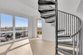 Located at 5570 Rosemead Blvd in Temple City, CA, this modern 2-bedroom, 1-bathroom unit offers a thoughtfully designed open floor plan with clean lines and a bright, contemporary aesthetic throughout. The kitchen serves as the heart of the home, featuring a large white quartz island with an undermount sink, stainless steel appliances including a gas range, built-in microwave, and side-by-side refrigerator, complemented by flat-front white cabinetry and pendant lighting. A stacked in-unit washer and dryer is conveniently tucked behind louvered doors nearby. A dramatic black spiral staircase adds a striking architectural focal point to the living area. Light-toned hardwood flooring runs throughout, enhancing the airy, cohesive feel of the space. The primary bedroom is generously sized, bathed in natural light from oversized floor-to-ceiling windows that frame sweeping views of the surrounding Temple City neighborhood. The second bedroom also features a window with natural light and outdoor views. The bathroom is cleanly finished with a white vanity, under-mount sink, and warm wood flooring. A dedicated closet completes the layout, offering practical storage. The overall ambiance is sleek, modern, and move-in ready.
