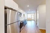 Located at 2500 Vantage Dr in Woodbridge, VA, this thoughtfully designed one-bedroom, one-bathroom residence offers a clean, modern aesthetic across a single-level floor plan. The open-concept living area seamlessly connects the kitchen, dining, and living spaces, creating an efficient and functional layout ideal for everyday living. The kitchen is a standout feature, showcasing stainless steel appliances including a refrigerator, range, microwave, and dishwasher, complemented by two-tone cabinetry — crisp white upper cabinets paired with darker lower cabinets — quartz countertops, a subway tile backsplash, and a deep undermount sink. Warm wood-look flooring flows throughout the main living areas, while large windows and a glass balcony door at the end of the living room invite abundant natural light and outdoor views. The bedroom is a comfortable retreat finished with plush carpeting and a bright window overlooking the outdoors. Four closets throughout the unit provide exceptional storage. The bathroom features a clean, all-white design with a soaking tub, tiled shower surround, a white vanity with quartz countertop, and matching wood-look flooring. In-unit laundry adds further convenience to this well-appointed residence.