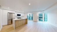 Located at 1470 Queen Street in Halifax, Nova Scotia, this modern unit offers a thoughtfully designed open-concept layout spanning a generous single floor. Light-toned hardwood flooring flows seamlessly throughout, creating a cohesive and airy aesthetic.

The kitchen is a standout feature, showcasing high-gloss white cabinetry, a marble-look quartz countertop with a waterfall-edge island, a subway tile backsplash, and stainless steel appliances including a refrigerator, electric range, and built-in microwave. The island provides both prep space and casual seating potential, and transitions naturally into the open living area.

The living room is bright and spacious, benefiting from large floor-to-ceiling windows and sliding glass doors that flood the space with natural light and offer views of the surrounding urban streetscape.

The bedroom is a well-proportioned, clean space with recessed lighting, light wood flooring, and a large window for natural light. Four closets are distributed throughout the unit, providing ample storage.

Both bathrooms are finished in a crisp, modern style with floating white vanities, stone-look countertops, large mirrors, and neutral tile. One bathroom features a walk-in shower with tile surround, while the second serves as a full bath. The overall ambiance is clean, contemporary, and light-filled.