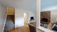 This two-story home offers a thoughtfully designed layout across two levels, combining comfort and functionality. The main level features warm hardwood flooring throughout the living and dining areas. The living room is anchored by a striking full-height brick fireplace, adding character and a cozy focal point to the space. Large windows allow ample natural light to fill the room, while an open sightline connects to the dining area, which accommodates a dining set beneath a ceiling light fixture. The kitchen is well-equipped with warm wood cabinetry, granite countertops, a stainless steel appliance suite including a refrigerator, dishwasher, microwave, and range, and tile flooring. A central window above the sink brings in additional natural light. The upper level hosts spacious bedrooms finished with plush carpeting and neutral tones. Each bedroom benefits from multiple windows offering views of the surrounding greenery. The bathroom features tile wainscoting, a granite-topped vanity with wood cabinetry, and a windowed shower/tub combination. A carpeted staircase connects the two floors, completing this well-maintained and inviting home.