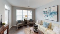 This single-floor residence offers a well-balanced layout across one bedroom and one bathroom, designed with modern finishes and a cohesive, neutral aesthetic throughout. The living room serves as a welcoming central gathering space, featuring dark hardwood-style flooring, soft gray walls, and a large picture window that allows generous natural light to fill the room. The open layout accommodates comfortable seating arrangements and provides a relaxed, airy atmosphere.

The kitchen is outfitted with dark espresso cabinetry that reaches toward the ceiling, offering ample storage, complemented by light speckled granite-style countertops and stainless steel appliances, including a range, built-in microwave, and a double-basin sink. The contrast between the dark cabinetry and light countertops creates a clean, contemporary look.

The bedroom is carpeted and features a ceiling fan, a window providing natural light, and direct access to a walk-in closet equipped with built-in shelving and hanging space—offering notable storage capacity.

The bathroom is finished with dark cabinetry, a granite-style vanity countertop, wood-style tile flooring, and a full soaking tub with a shower, framed by a clean white surround and accented with brushed nickel fixtures throughout.
