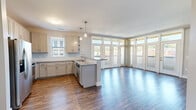 This single-floor, 2-bedroom, 2-bathroom residence offers a well-designed open-concept layout with modern finishes throughout. The combined kitchen and living area serves as the heart of the home, featuring rich hardwood-style flooring, crisp white cabinetry, granite countertops, stainless steel appliances, and a central island with pendant lighting overhead. A sweeping bay of floor-to-ceiling windows and glass doors floods the living area with natural light and provides views of the surrounding landscape, creating an airy and inviting atmosphere.

A wide hallway connects the main living space to the private quarters, maintaining a clean, neutral palette of soft grays and warm whites throughout. The spacious primary bedroom includes plush carpeting, a ceiling fan, and windows that invite natural light, complemented by a dedicated walk-in closet featuring built-in shelving and additional natural light from a vertical window. The second bedroom is equally comfortable, also finished with carpet and a ceiling fan.

Both bathrooms are tastefully appointed, with one featuring dark tile flooring, a single vanity, and a tub-shower combination. An in-unit laundry area houses a stacked washer and dryer, adding convenience. The layout is efficiently organized and provides ample storage, making this a highly functional and comfortable living space.