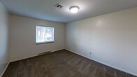 Located at 425 Waupelani Drive in State College, Pennsylvania, this single-floor apartment offers 850 square feet of living space across three bedrooms, one bathroom, and a connecting hallway. The layout is practical and functional, as seen in the dollhouse view, with a kitchen positioned centrally featuring wood cabinetry, granite-style countertops, and stainless steel appliances including a refrigerator and stove. The bedrooms are carpeted throughout and finished with neutral white walls and standard ceiling-mounted light fixtures. The primary bedroom measures 150 square feet and includes a double-door closet, offering ample storage. A second bedroom benefits from a window overlooking greenery, bringing in natural light, while a third smaller bedroom features a high window. Each room is connected via a hallway with hard surface flooring. The shared full bathroom is equipped with a tiled tub-shower combination. The unit's clean, simple design provides a versatile canvas suitable for a range of living arrangements, making it a straightforward and functional residence in the State College area.