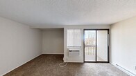 Located at 12 Ridgefield Dr in Middletown, CT, this single-floor unit offers a practical and efficiently laid-out living space. The carpeted living room provides a comfortable, neutral setting with textured ceilings, a wall-mounted air conditioning unit, and a sliding glass door that opens onto a private balcony overlooking wooded surroundings — bringing in natural light and outdoor views. The open-concept kitchen connects directly to the living area through a pass-through opening, and features white cabinetry, dark stone-finish countertops, a white electric range, and tile flooring. A dedicated closet near the living space houses the water heater alongside storage space, with additional closet access nearby. The full bathroom is cleanly finished with tile flooring, a white vanity with under-cabinet storage, a mirrored medicine cabinet with overhead lighting, and standard fixtures. Throughout the unit, neutral wall tones and consistent finishes create a cohesive, understated aesthetic. The layout makes efficient use of the available footprint, providing all essential living functions within a well-organized single-level floor plan.