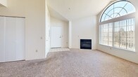 Located at 7929 W Mansfield Pkwy in Lakewood, Colorado, this single-floor, 2-bedroom, 2-bathroom residence offers a well-organized layout designed for comfortable everyday living. The living room serves as the focal point of the home, distinguished by soaring vaulted ceilings and a striking arched window that floods the space with natural light. A fireplace anchors the room, adding warmth and character, while plush carpeting underfoot contributes to a cozy atmosphere. A tiled entryway transitions smoothly into the living area.

The kitchen is positioned adjacent to the living room and features a pass-through counter that maintains visual connectivity between the two spaces. Dark espresso cabinetry contrasts with light countertops, and white appliances — including a range, microwave, and refrigerator — provide full functionality. Wood-look flooring runs throughout the kitchen.

Both bedrooms are carpeted and feature vertical blinds over windows that admit natural light. The generously sized primary bedroom includes access to a closet. The two bathrooms each offer a tub-shower combination with tiled surrounds, wood-look flooring, and dark vanity cabinetry with light countertops, maintaining a consistent design aesthetic throughout the home.