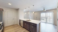 Located at 4781 Transit Rd in Depew, NY, this well-appointed 2-bedroom, 1-bathroom unit offers a thoughtfully designed single-floor layout with modern finishes throughout. Light-toned luxury vinyl plank flooring flows seamlessly across all living areas, creating a clean and cohesive aesthetic.

The kitchen serves as the heart of the home, anchored by a large island with a quartz countertop, undermount sink, and stylish pendant lighting. Dark espresso cabinetry pairs elegantly with the light countertops, while stainless steel appliances — including a range, over-the-range microwave, refrigerator, and dishwasher — complete the space.

The open layout connects the kitchen to the living area, which features a sliding glass door leading to a private balcony with outdoor views. The spacious primary bedroom is filled with natural light from dual corner windows, while the second bedroom includes a double-door closet and its own large window. A dedicated closet provides additional storage.

The full bathroom is finished with a glass-enclosed shower/tub combo, a dark-toned vanity with a single sink, and a well-lit mirror. A dedicated laundry area with a top-load washer and overhead shelving adds everyday convenience. Neutral tones and clean lines throughout give this unit a bright, modern feel.